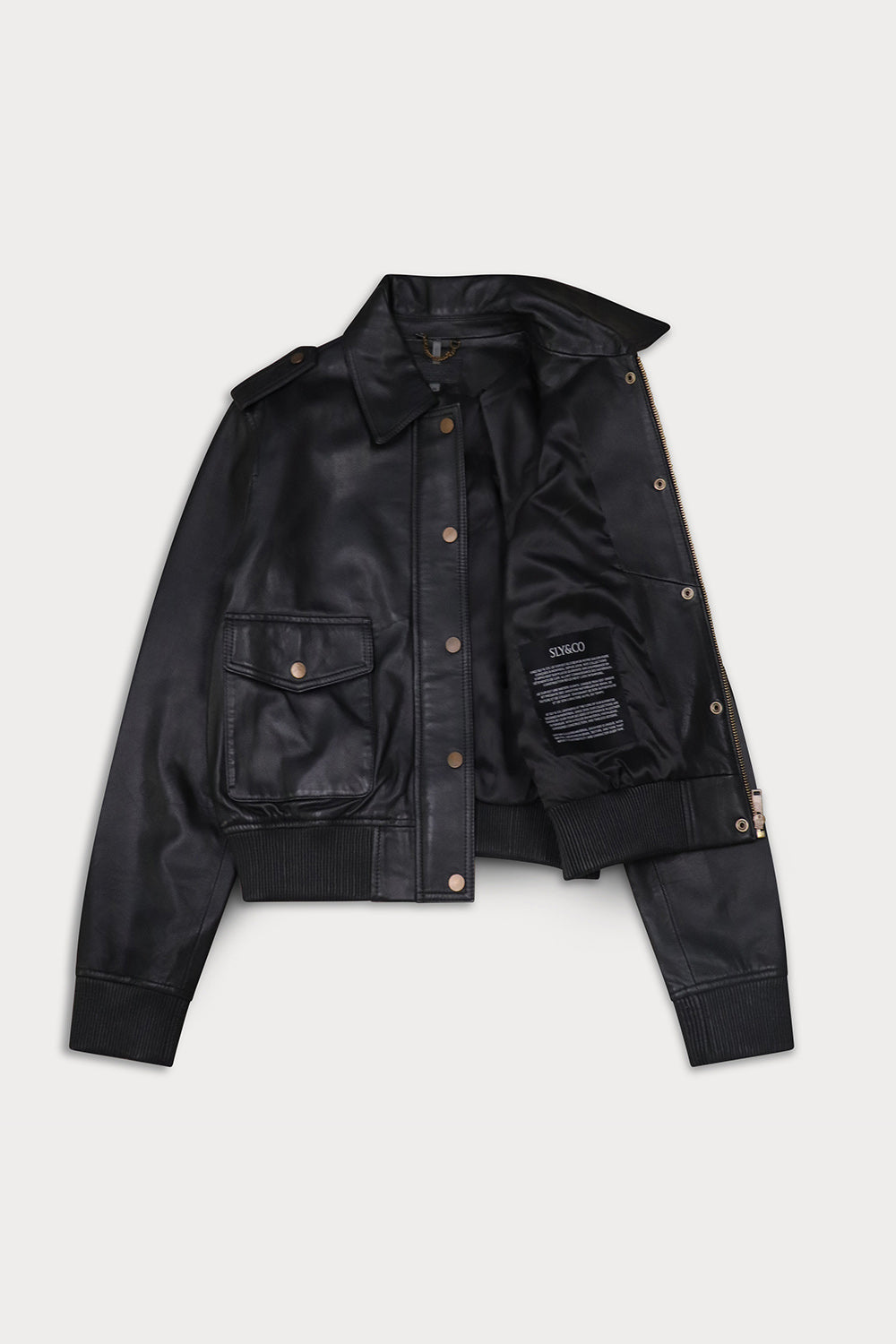 A black leather jacket  button-up front, and two front flap pockets with brass-tone snaps, displayed open. Amelia -Sly&Co
