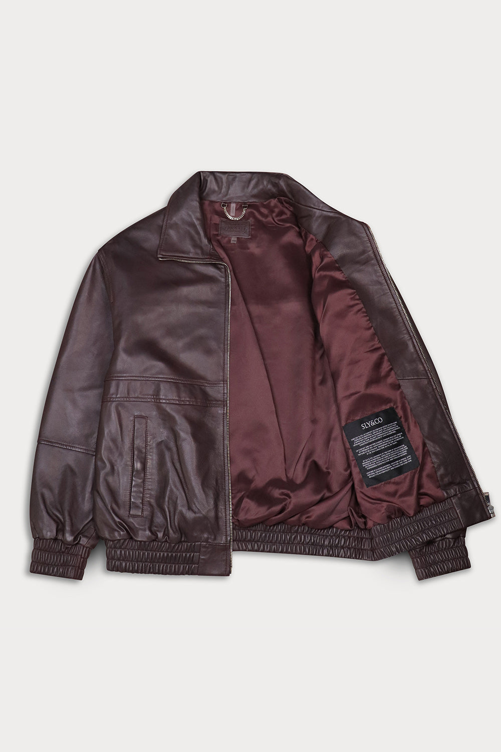 A dark brown leather jacket with a matching satin-lined interior, laid flat against a light gray background.