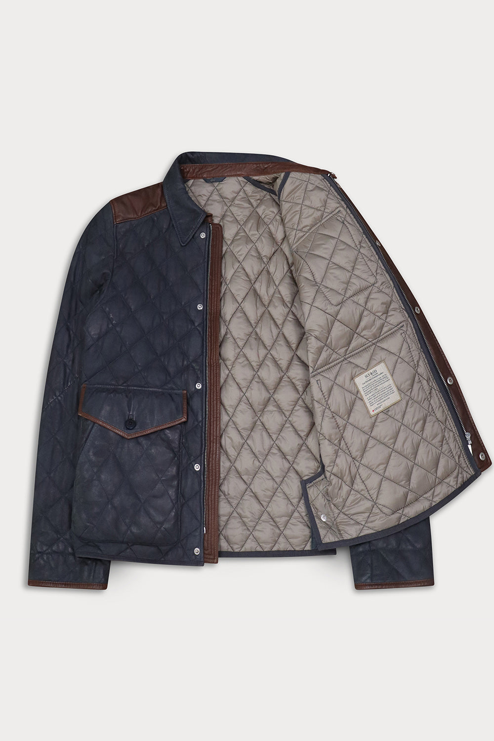 A navy blue quilted jacket with brown leather-like shoulder and cuff accents, shown open to reveal a light gray quilted interior lining 