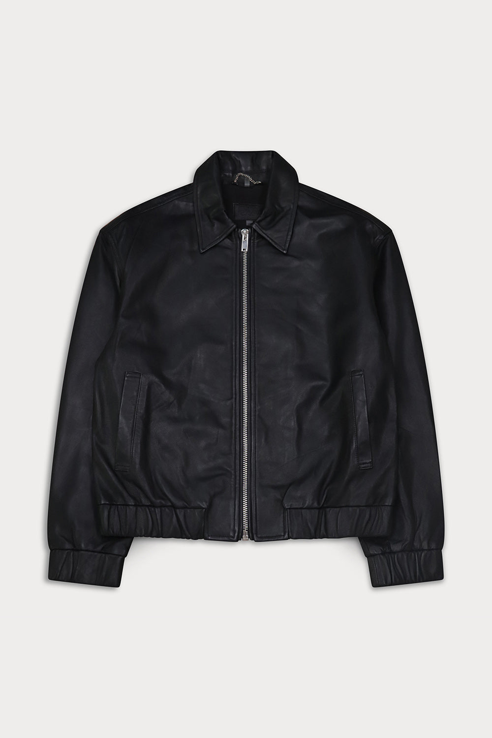 A black leather bomber jacket with a full front zipper, pointed collar, and ribbed cuffs and hem. Ciara- Sly&Co