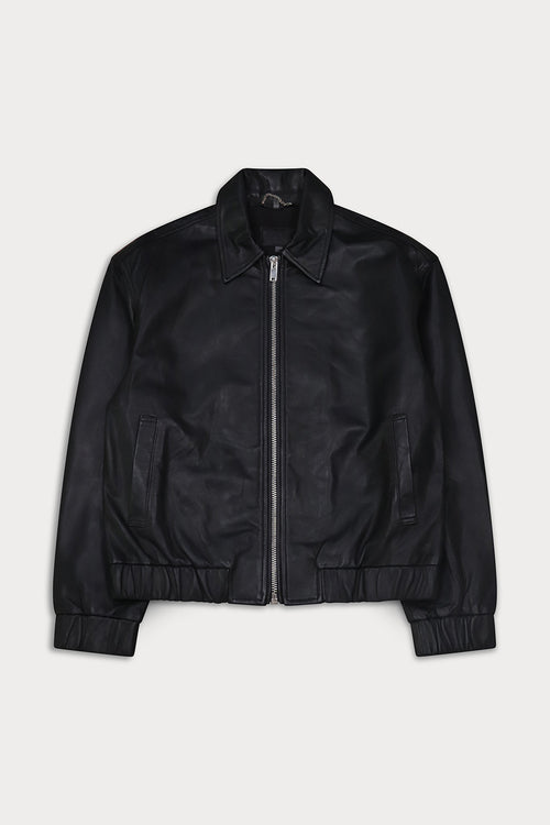 A black leather bomber jacket with a full front zipper, pointed collar, and ribbed cuffs and hem. Ciara- Sly&Co