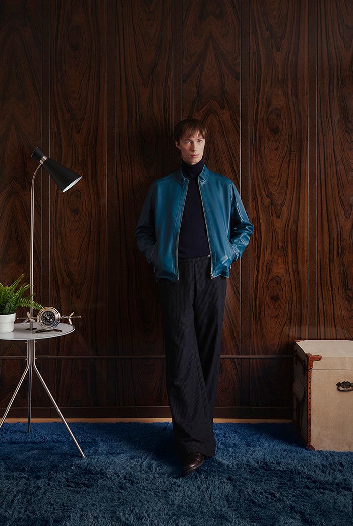 A male model wearing an ocean-blue leather jacket. Clark-Sly&Co