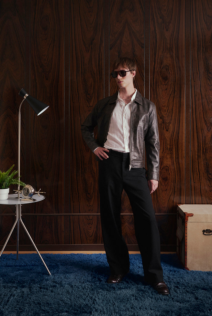 A model wearing a black leather jacket, white shirt, black trousers.