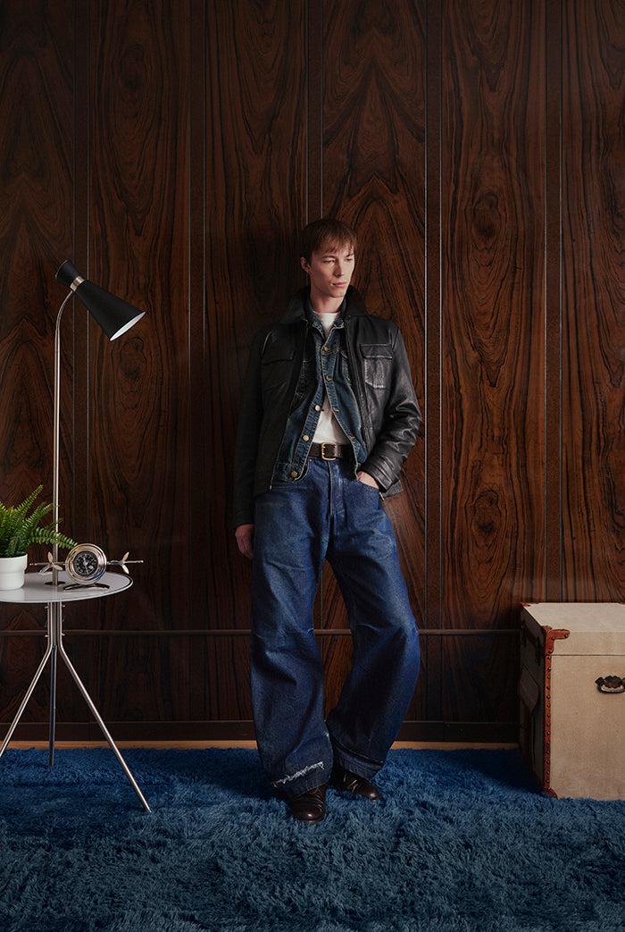 A male model wearing a black leather jacket with a zippered front, collar, two chest flap pockets, an interior vest. Sandro-Sly&Co