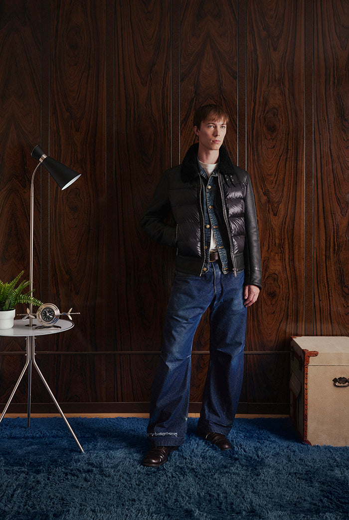A model stands in a room wearing a black quilted shhepskin leather puffer jacket from Sly&Co